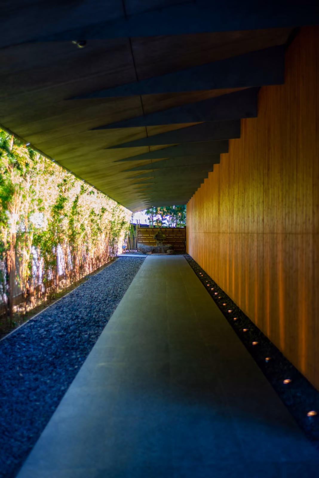 L'allée d'entrée du musée Nezu sous un long auvent, entre une haie de bambous et un mur de lattes de bois dessiné par Kengo Kuma