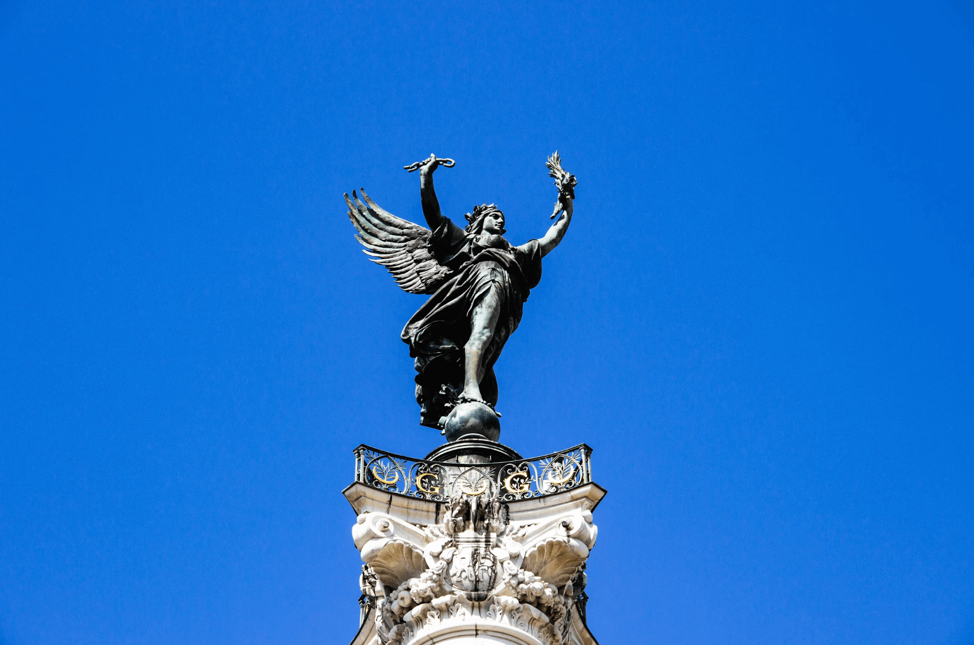 Statue ailée sur le Monument aux Girondins, Place des Quinconces à Bordeaux, capturée en contre-plongée sous un ciel bleu clair.