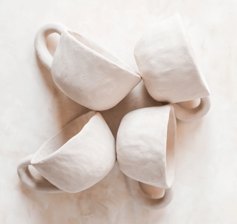Quatres tasses en céramique blanches. Les quatres tasses sont allongées sur le côtés.
