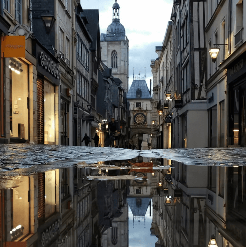 Rue pavée du Gros-Horloge avec l’horloge monumentale visible en arrière-plan et ses boutiques tout du long.