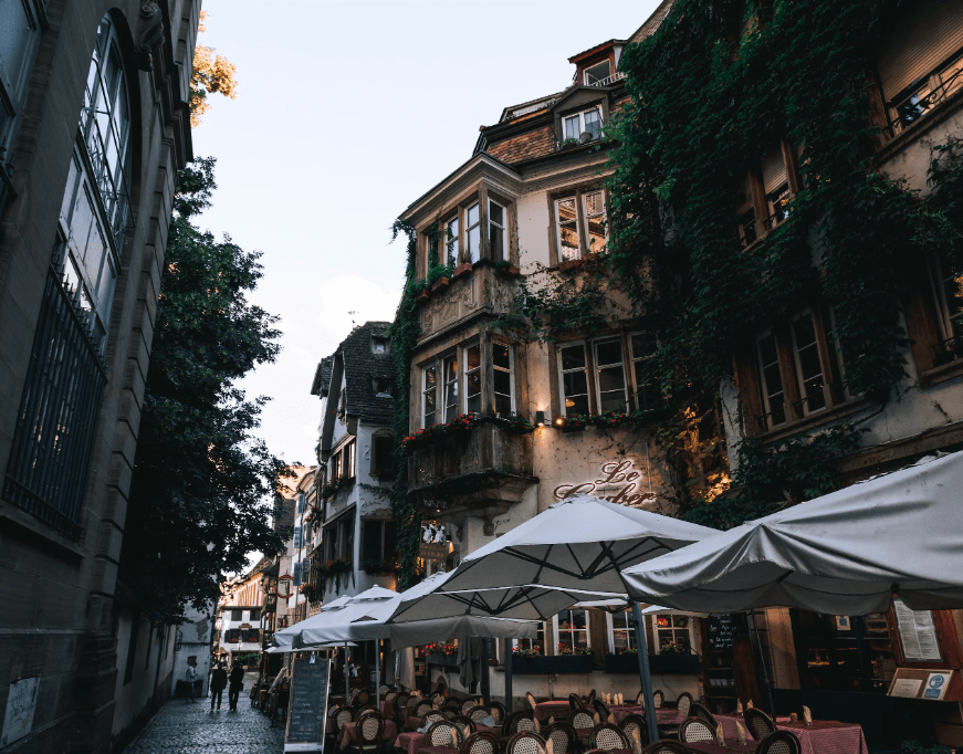 Rue pittoresque de Strasbourg avec des bâtiments historiques couverts de vignes et une terrasse de café animée